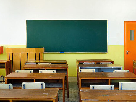 Ein leeres Klassenzimmer mit Blick auf eine grüne Tafel