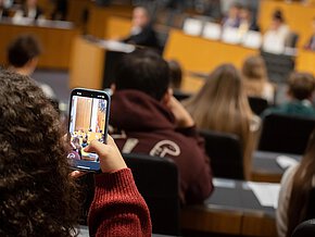 Junge Frau mit Mobiltelefon im Sitzungssaal des Nationalrates