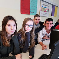 Schüler und Schülerinnen vor ihrem gemeinsamen Computern.