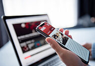 Person nutzt Handy und Laptop zur Authentifizierung