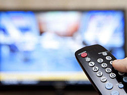 Jemand bedient den Fernseher mit einer Fernbedienung.