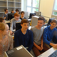 Schülerinnen und Schüler vor ihren gemeinsamen Computer-Arbeitsplätzen.