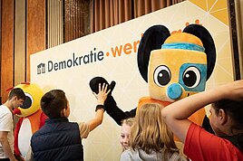 Werkstattprofis im High-Five mit einem Maskottchen